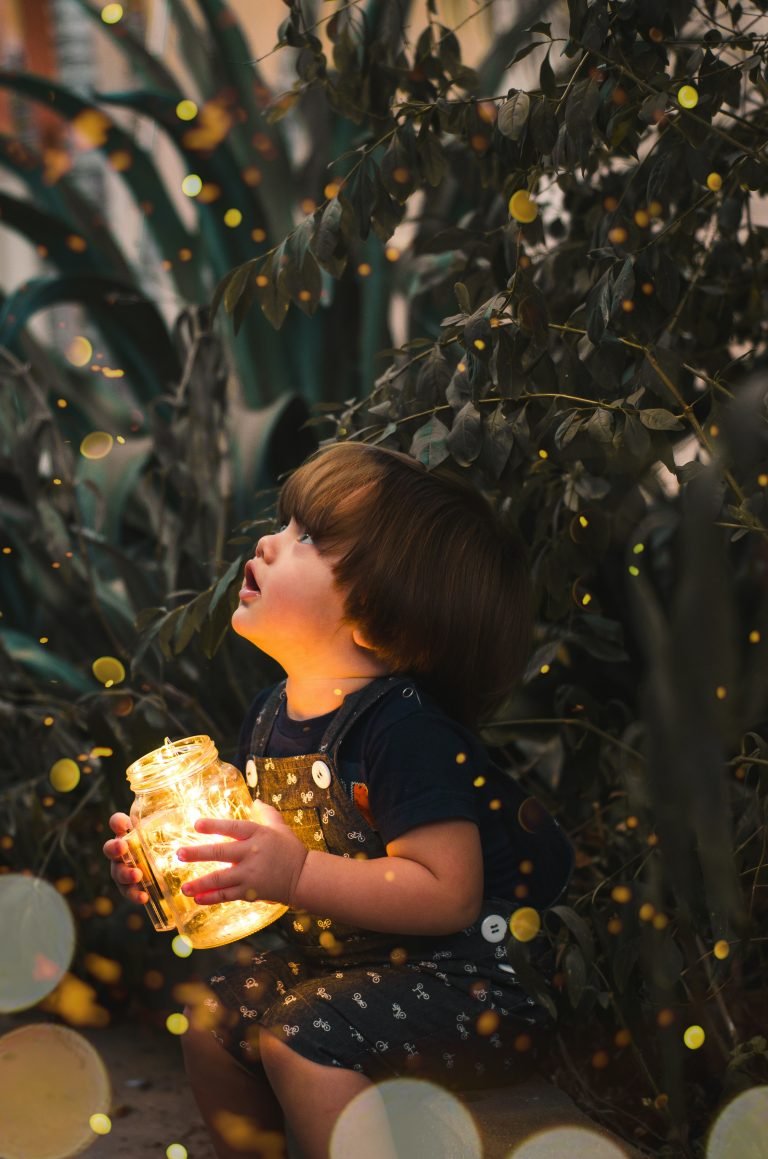 Child Holding Clear Glass Jar With Yellow Light scaled