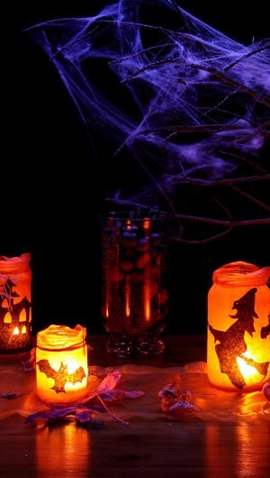 jack o lantern beside glass jar with candle autumn black scaled